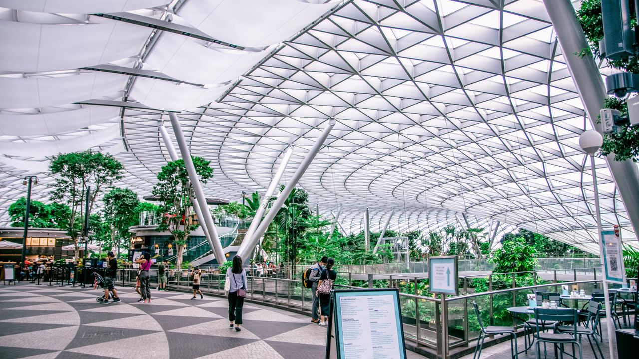 Travellers walking under the glass dome of the Jewel terminal at Changi Airport, Singapore